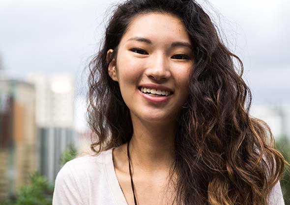 Young woman smiling outside.